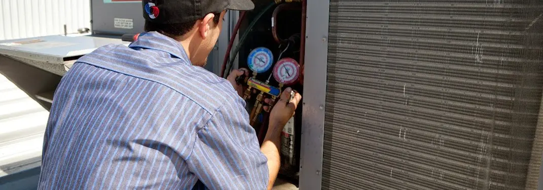 HVAC technician servicing a condenser unit in Little Canada